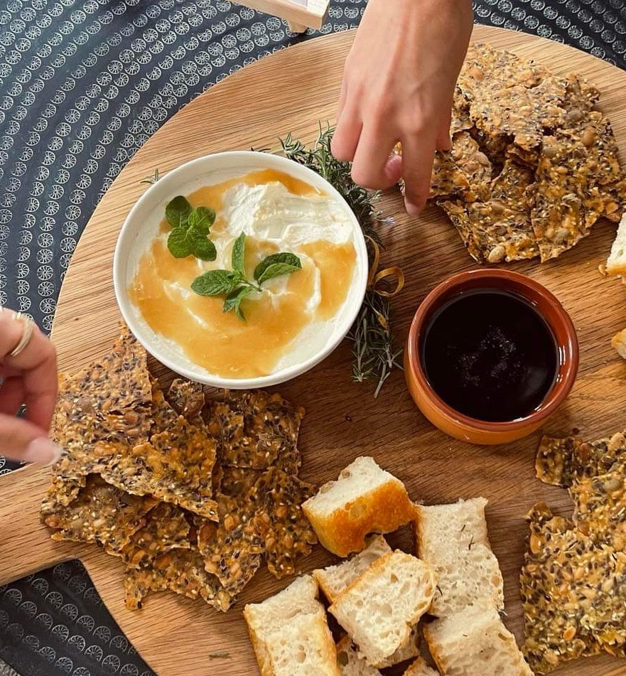 Freshly baked Kiki crackers styled on a platter with dips, cheese and toppings.